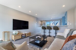A modern living room with a flat-screen TV, a wooden cabinet, a coffee table, and a sofa.