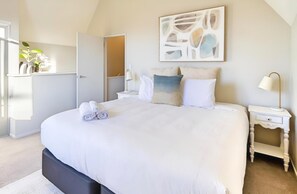 Un dormitorio con una cama grande, una mesita de noche y un cuadro en la pared.