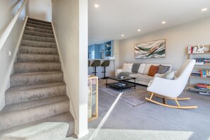 A staircase leading to a living area with a sofa, coffee table, and bookshelves.