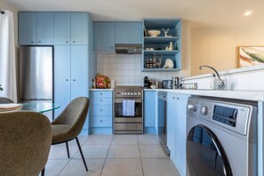 Une cuisine compacte équipée d’un lave-vaisselle, d’un four et d’un lave-linge.