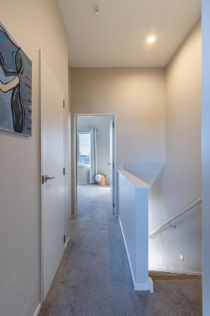 Ein Flur mit Teppichboden, einer weißen Tür und einem Gemälde an der Wand.