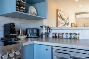 A modern kitchen with a coffee machine, toaster, kettle, and jars of spices.