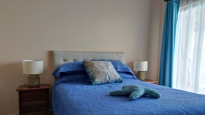 A neatly made bed with a blue quilt, two bedside lamps, and a nightstand with a lamp.