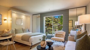 A modern bedroom with a bed, a sofa, a chair, a small table, and a window with a view of greenery. - Angani Studio - Elkhorn Resort Amenities Included (Sun Valley)