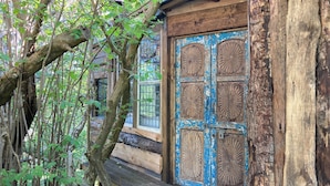 A rustic wooden building with a large, blue-framed door featuring circular designs. - Treehouse Cabin Wilderness Escape (Abergele)