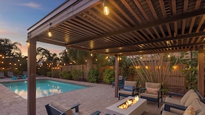 A covered outdoor area with a pool, seating, and string lights.