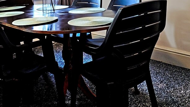 Ein Essbereich mit einem runden Tisch, schwarzen Stühlen, einer Blumenvase und zwei Wandbildern.