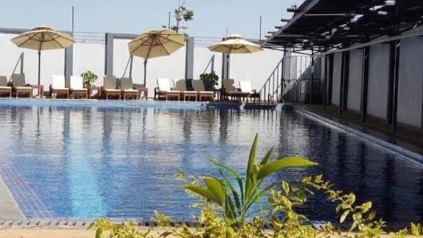 A swimming pool with lounge chairs and umbrellas, surrounded by a covered walkway. - Luxurious & Exclusively furnished Suite -UN Blue Zone, Child Friendly Apt. (Nairobi)
