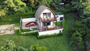 A two-story house with a thatched roof, a balcony, and a hot tub. - Tropical Paradise, Deluxe duplex cabin nestled in the majesty of the mountains (Anapoima)