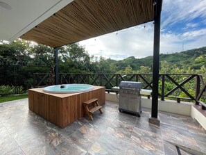 A hot tub and grill on a covered patio with a view of lush greenery. - Tropical Paradise, Deluxe duplex cabin nestled in the majesty of the mountains (Anapoima)