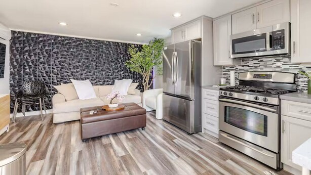 A modern kitchen with stainless steel appliances, a white countertop, and a geometric patterned wall.