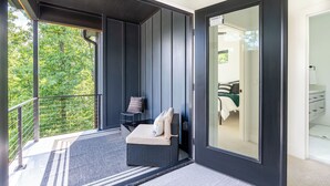 Een balkon met een zachte zithoek, een kleine tafel en een stoel.