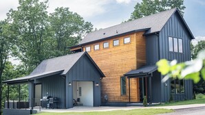 Een modern huis met twee verdiepingen, een garage, een overdekte veranda en een kleine tuin.