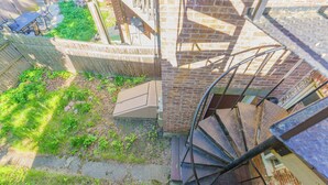 A spiral staircase leading to a brick building, a wooden fence, and a patio area with outdoor furniture. - Massive 5BD/4BA 3-Story Duplex @ Downtown Albany (Albany)
