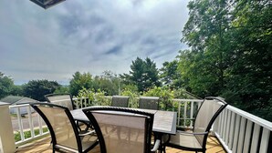 Une terrasse extérieure couverte, dotée d’une table et de chaises, et entourée d’une balustrade blanche.