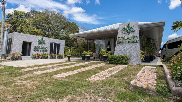 Hotel Solano, con un diseño moderno, presenta una entrada destacada y un espacio exterior cubierto.