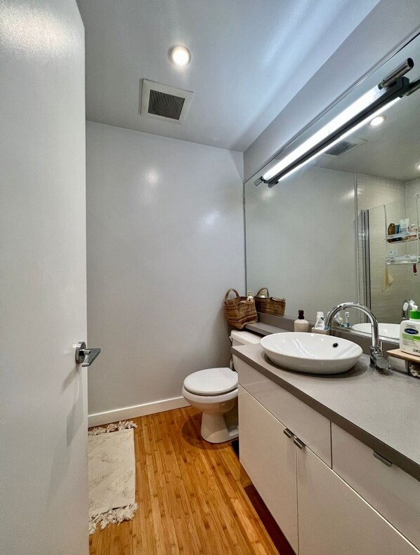 Een moderne badkamer met een wit toilet, een groot wastafelmeubel en een spiegel erboven.