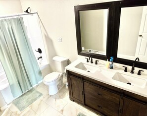Ein Badezimmer mit Dusche, Toilette, Waschbecken und einem großen Spiegel.