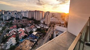 Une vue d’une ville au coucher du soleil, avec des immeubles de grande hauteur, une route et des quartiers résidentiels.