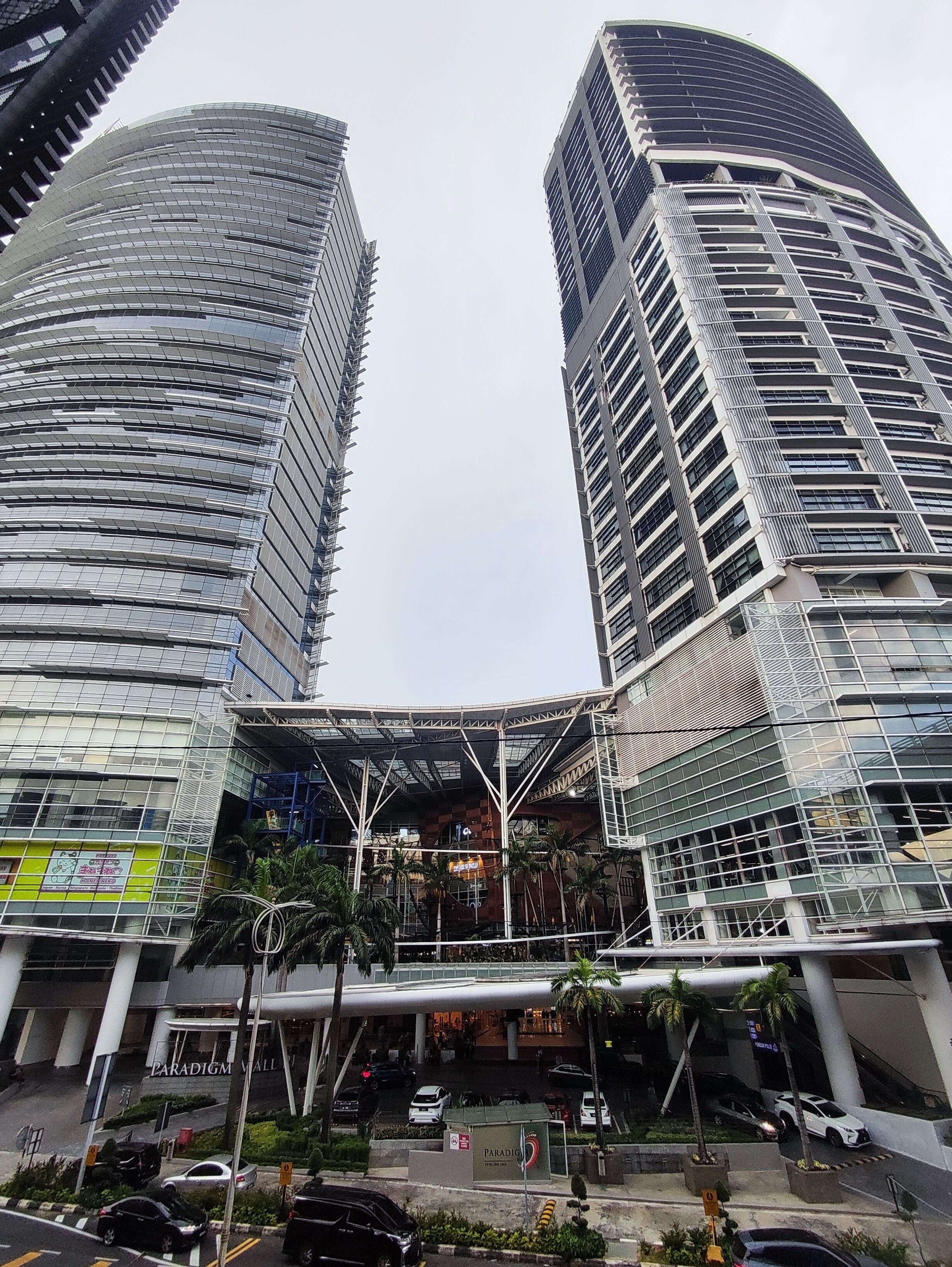 Deux immeubles modernes de grande hauteur, dotés d’un atrium central et entourés de verdure.