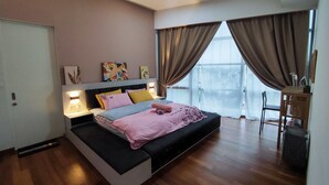 Une chambre à coucher moderne, équipée d’un lit, de lampes de chevet, d’un ventilateur de plafond et offrant une vue sur l’extérieur grâce à de grandes fenêtres.