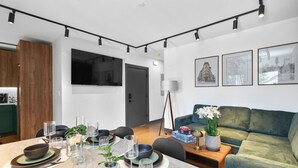 Ein modernes Wohnzimmer mit Essbereich, einer Couch und einem an der Wand befestigten Fernseher.