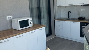 A compact kitchen with white cabinets, a microwave, and a black coffee maker on the counter. - Modern seaview apartment just 5 min from restaurants and markets, free parking!” (Vlora)