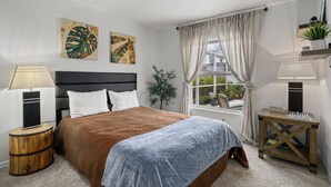 A bedroom with a bed, a bedside lamp, a window with curtains, and artwork on the wall. - Serenity Heaven Gateway/Pool/Sauna/Golf course (Bradenton)
