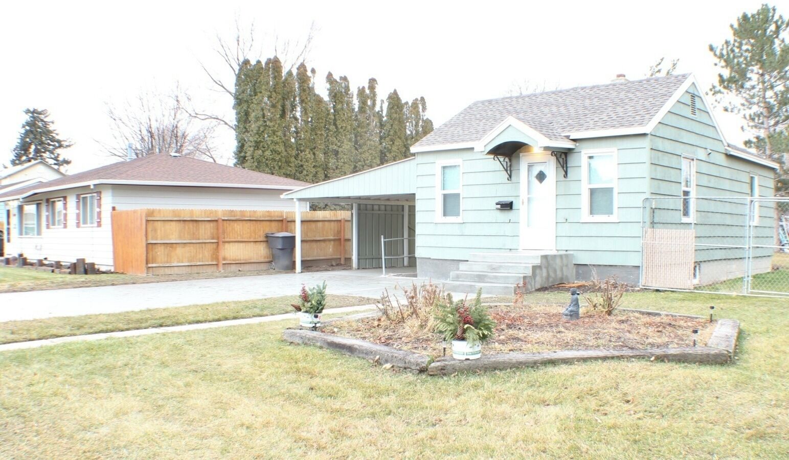 Une maison à deux étages avec un garage, un porche à l’avant et un petit jardin.