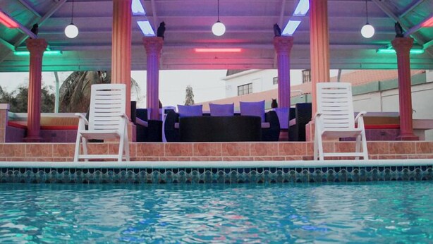 A pool area with a covered seating area, columns, and a tiled roof. - Emporis Resort  (Arouca)