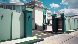 A gated entrance with a modern building featuring a curved facade and a flat roof. - Emporis Resort  (Arouca)