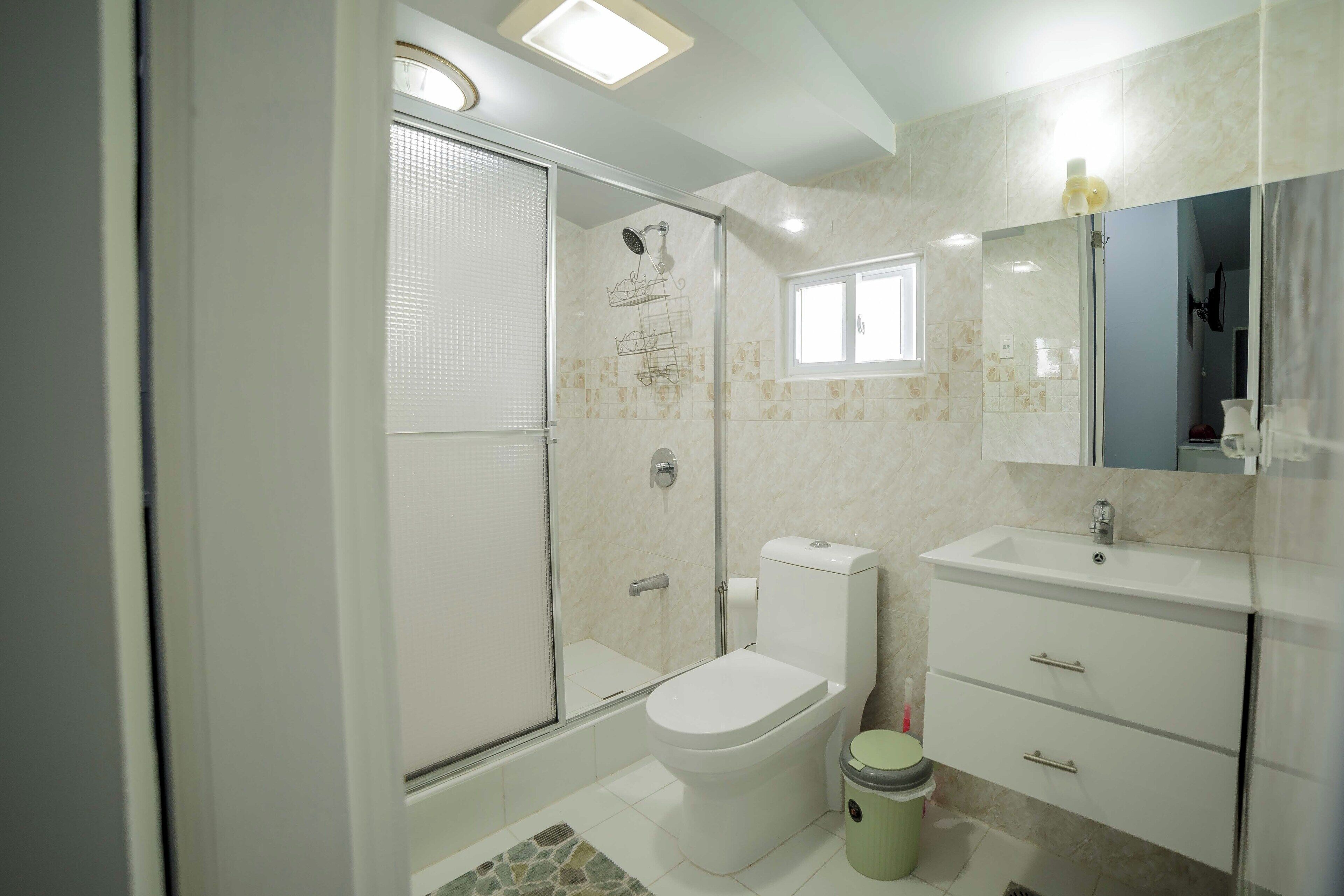 A bathroom with a shower, toilet, sink, and a mirror.