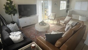 A living room with a TV, sofas, a coffee table, and a large plant.