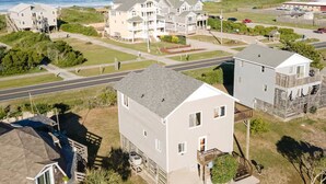 A coastal residential area with multiple houses, a road, and a beach in the background.