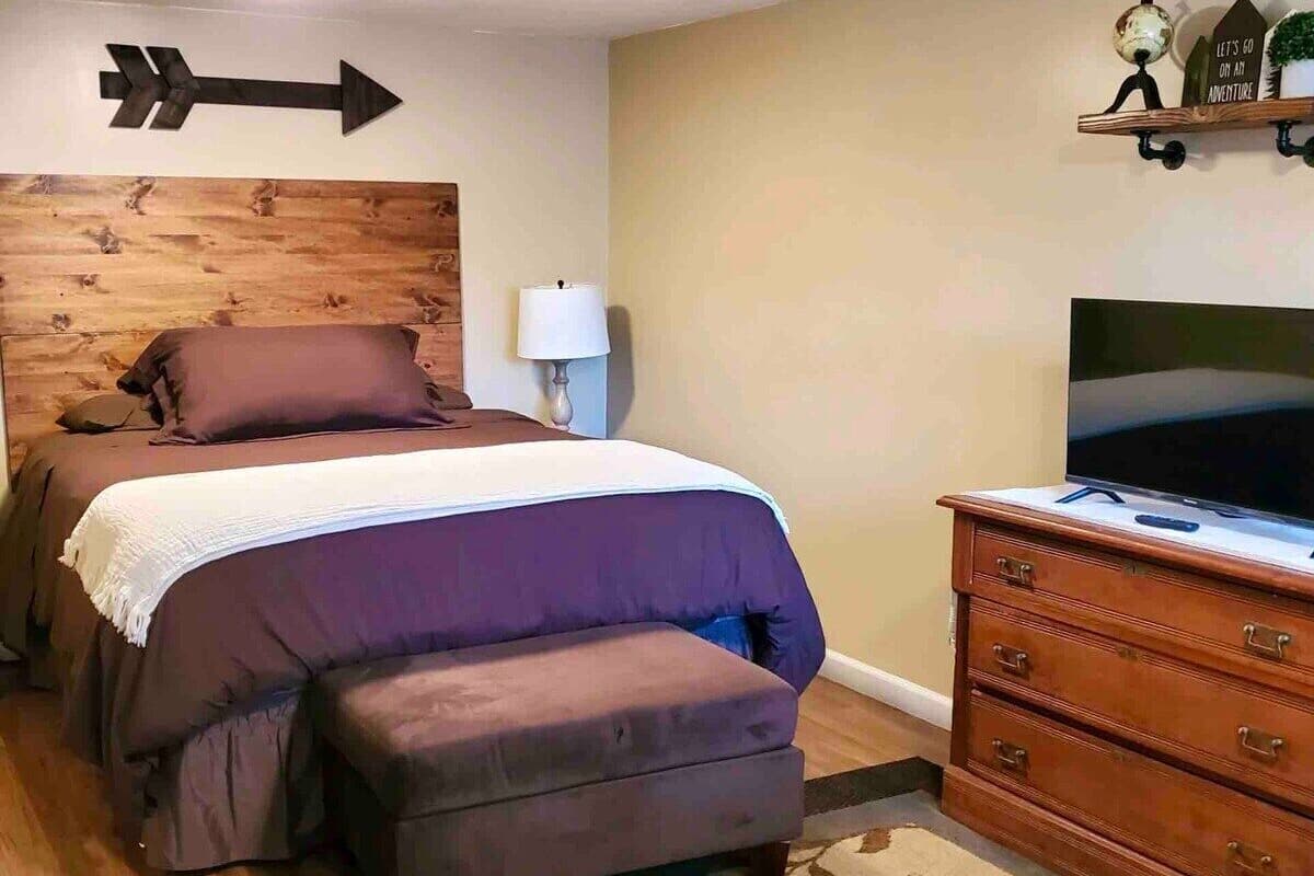 A bedroom with a bed, a dresser, a television, and a directional sign on the wall.