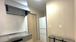 A compact kitchen with a built-in oven, a microwave, and a stainless steel range hood. There are two trash bins and a refrigerator. - SANTE 4073 STAY & SAUNA HAKATA ISLAND 1 (Imabari)