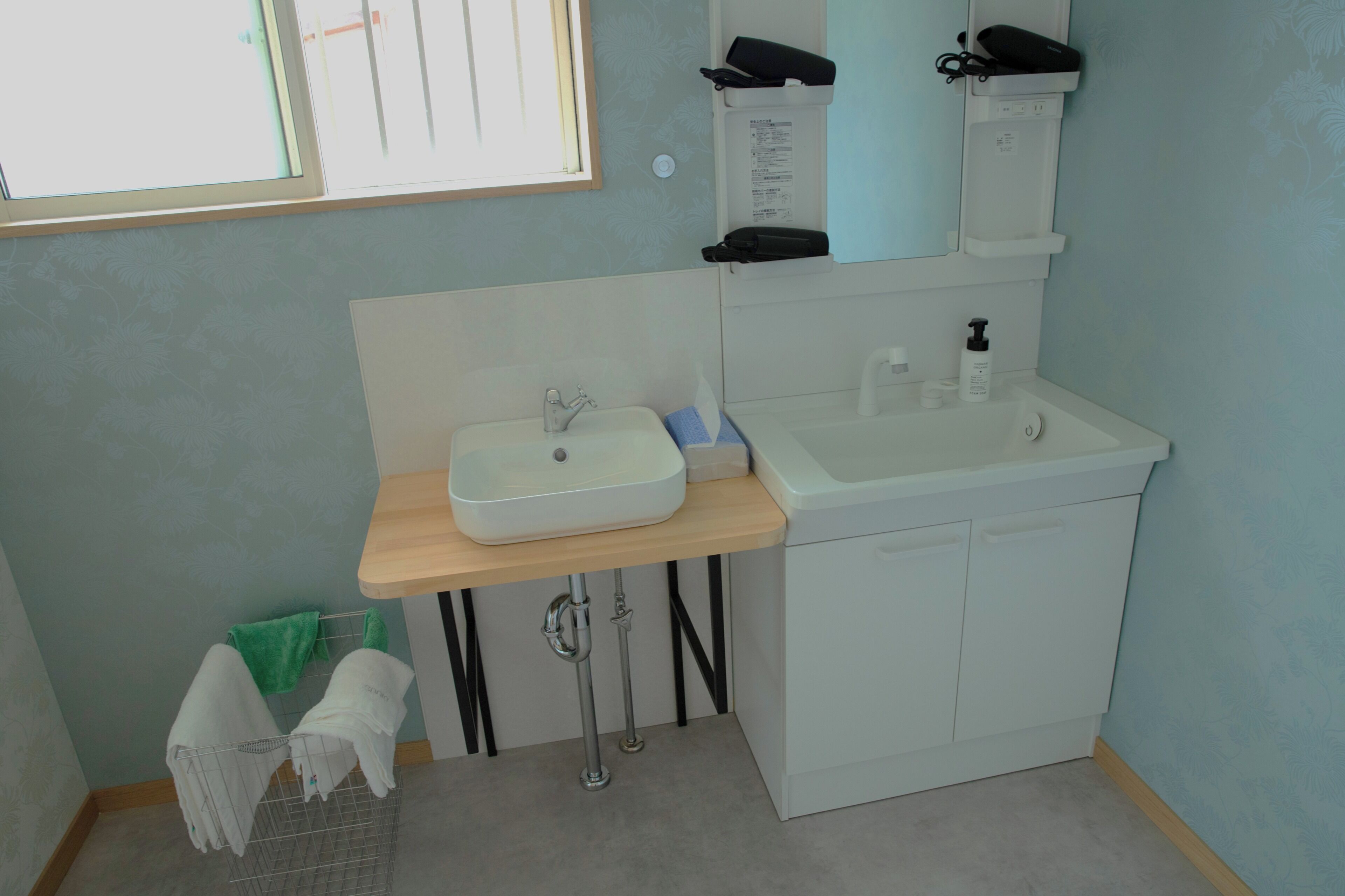 Een badkamer met een wit wastafel, een spiegel en een handdoekhouder.