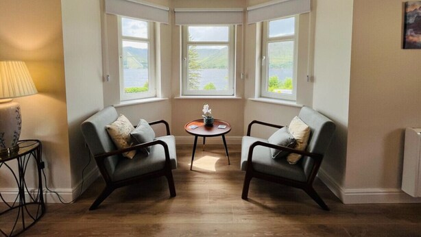 Een hoekappartement met twee fauteuils, een bijzettafeltje en een lamp.