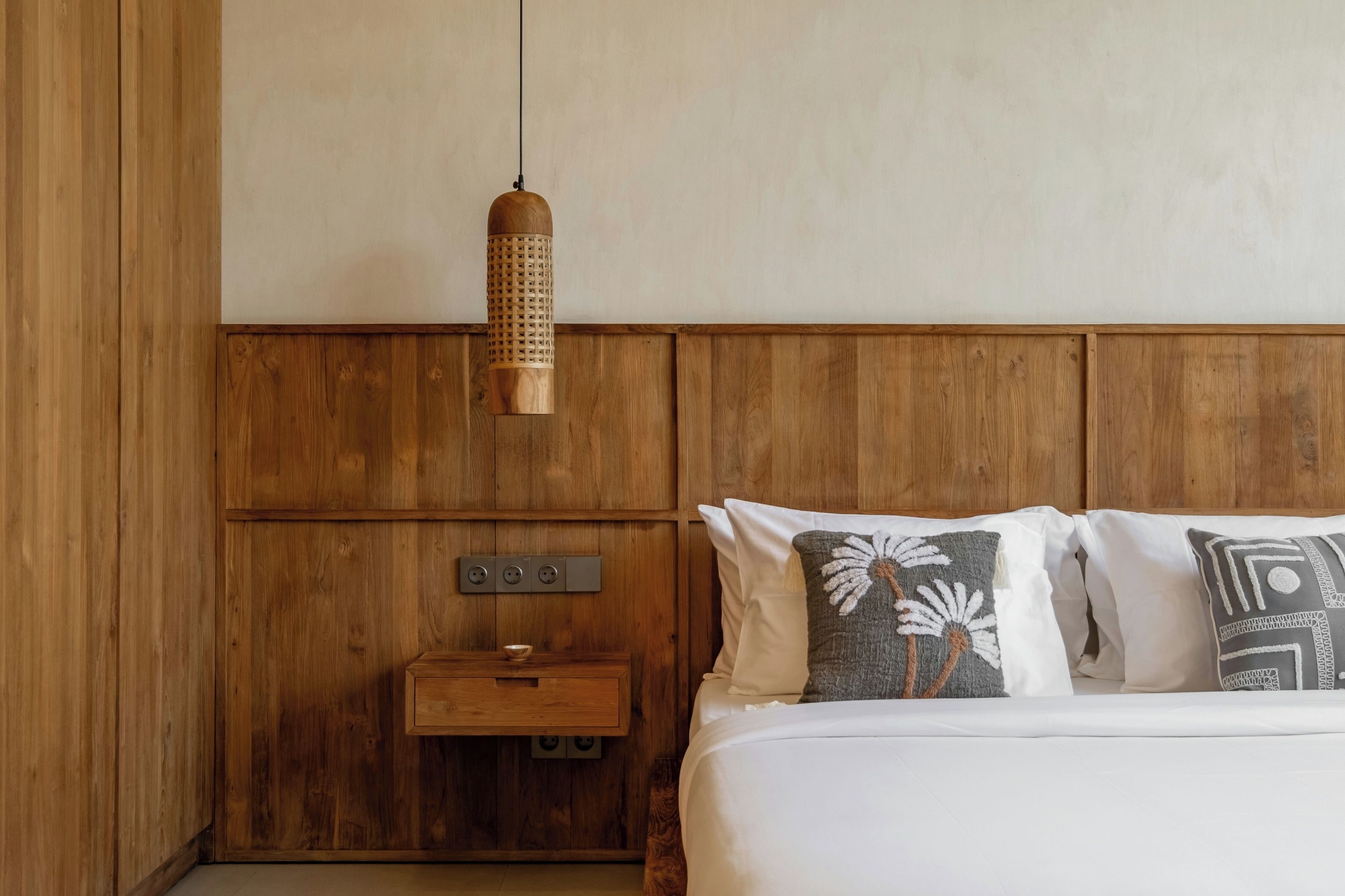A wooden-paneled room with a bed, a nightstand, and a hanging light fixture.