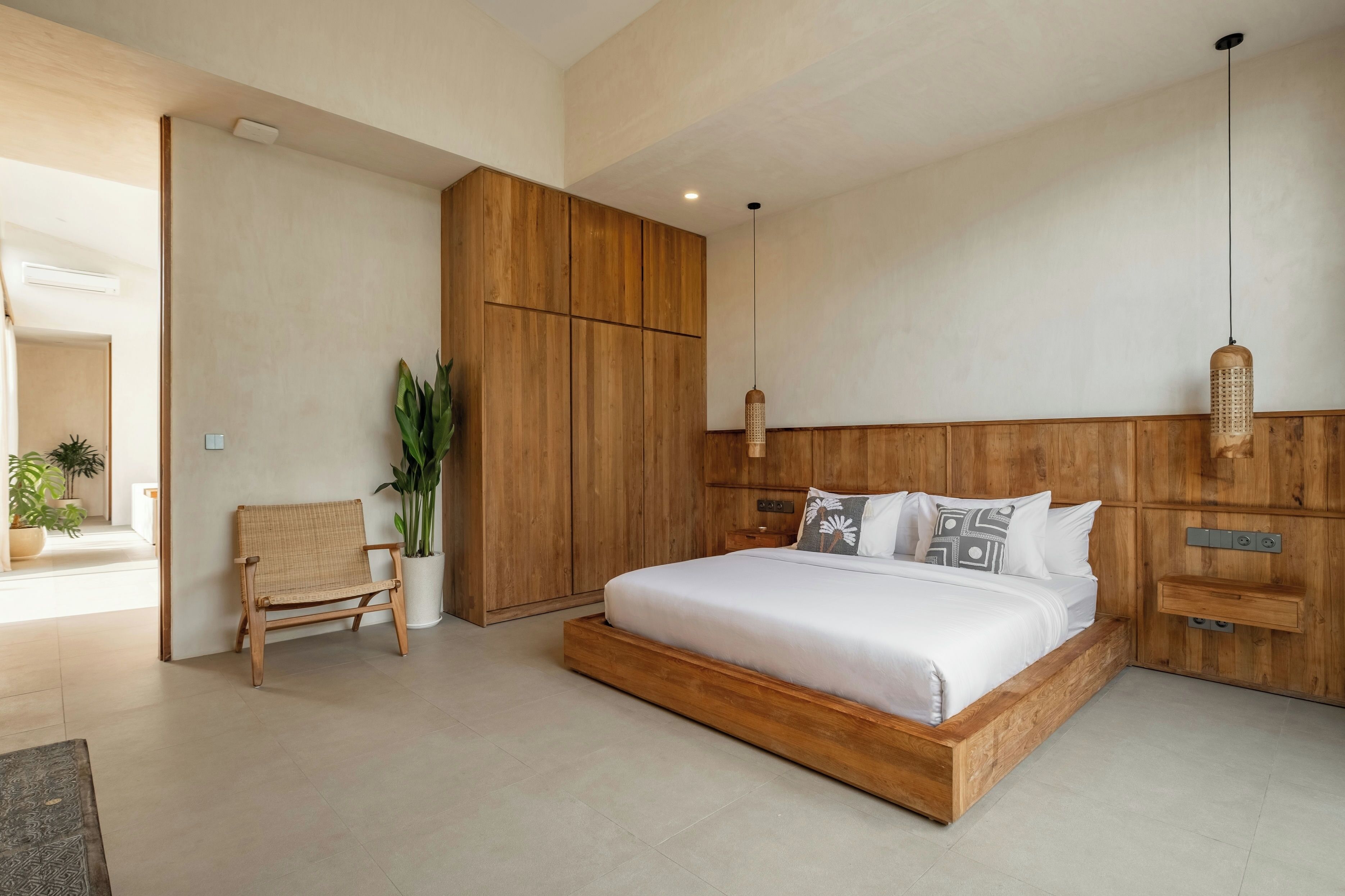 Camera da letto moderna con struttura letto e armadio in legno, una panca e un lampadario.