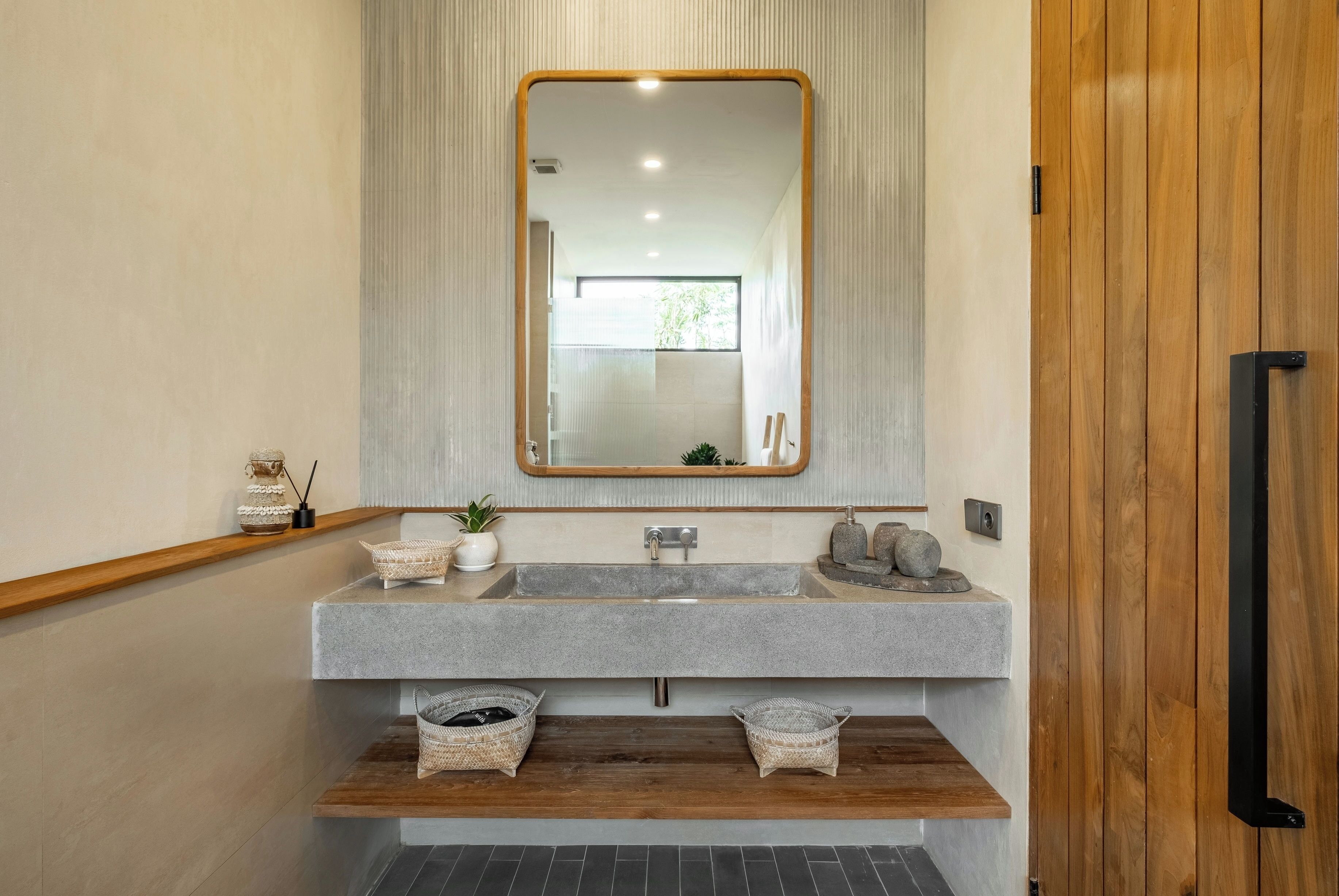 A bathroom with a large mirror, two sinks, and a wooden shelf with baskets.