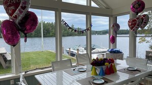 A dining area with a view of a lake, balloons, and a birthday banner.