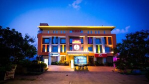 Een hotel met een centraal geplaatste klok, meerdere verdiepingen en een bord ervoor.