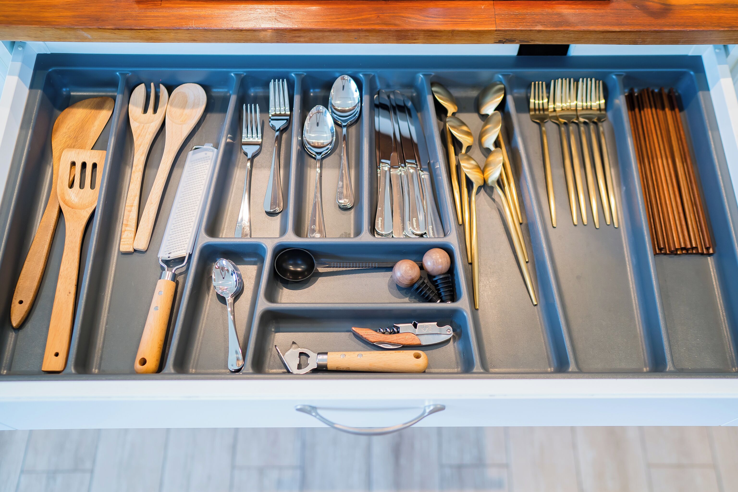 A drawer with various kitchen utensils and tools organized in compartments.