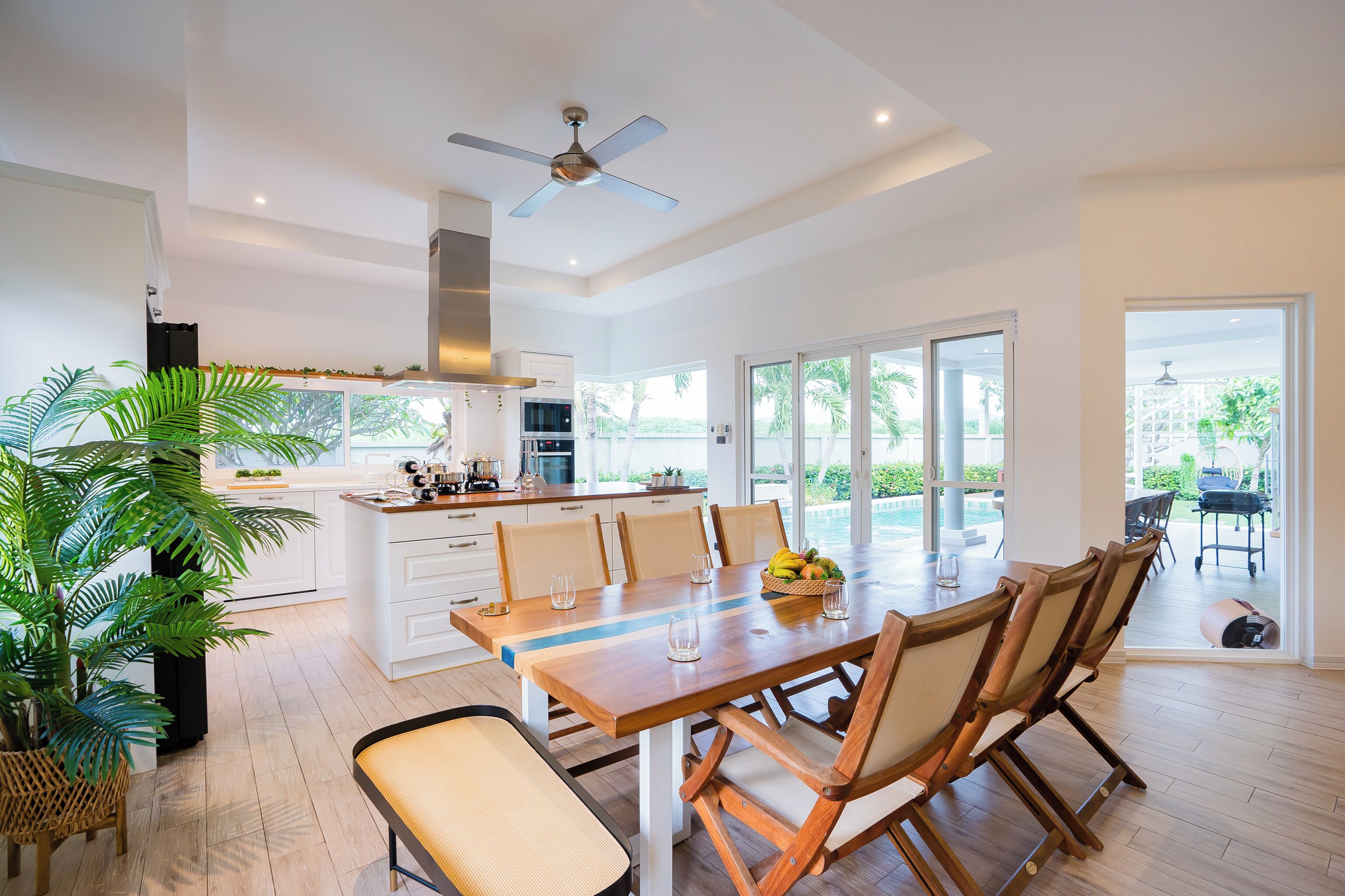 A spacious kitchen with white cabinets, a dining table with chairs, and a ceiling fan.