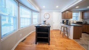 Una cocina con una isla central, armarios de madera y un reloj en la pared.