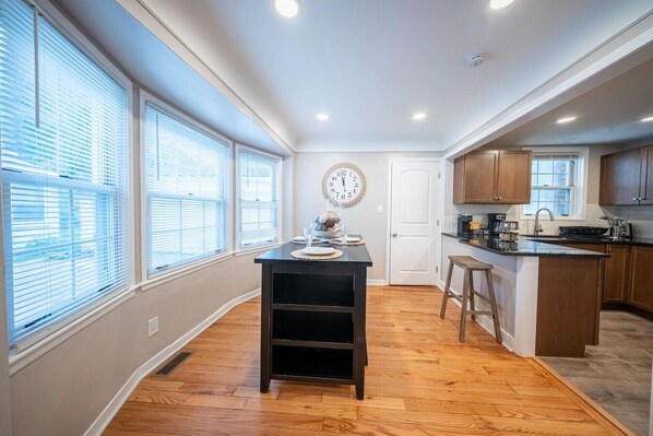 A kitchen with a central island, wooden cabinets, and a clock on the wall.