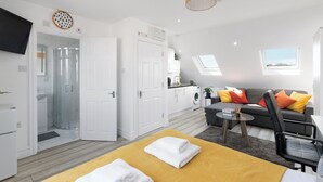 Un appartamento moderno con zona giorno, cucina e cabina doccia in vetro.