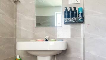 Un bagno con un lavandino bianco, uno specchio sopra e articoli da toilette a parete.