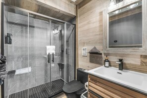 Une salle de bain moderne avec une douche à parois de verre, un lavabo blanc et des meubles en bois.